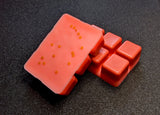 clamshell shaped wax with a red base and neon orange top, topped with orange square glitter.