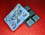 clamshell shaped wax that is colored blue with a green tint and green flaky glitter on top.