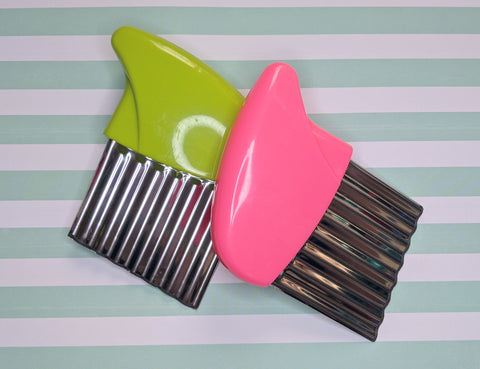 two metal crinkle cutter with a plastic handle, one colored green and one colored pink.