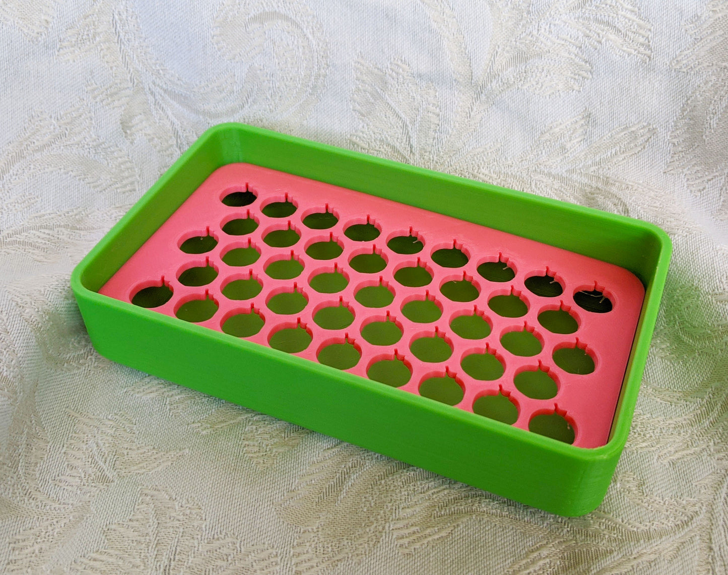 Neon green plastic soap dish with a neon pink tray with peach shaped drainage holes.