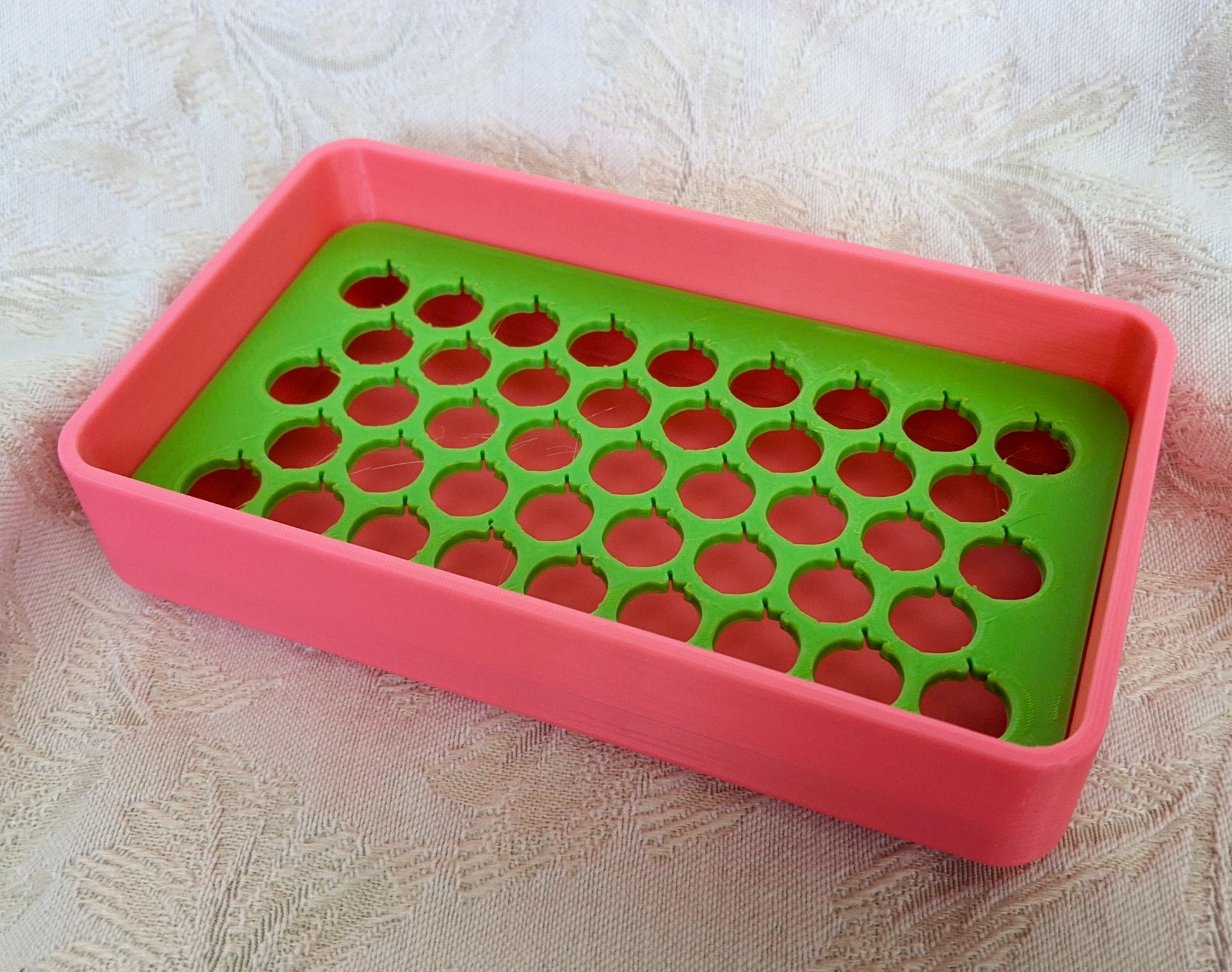 Neon pink plastic soap dish with a neon green tray with peach shaped drainage holes.