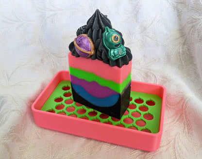bar of soap sitting in neon pink and green soap dish.