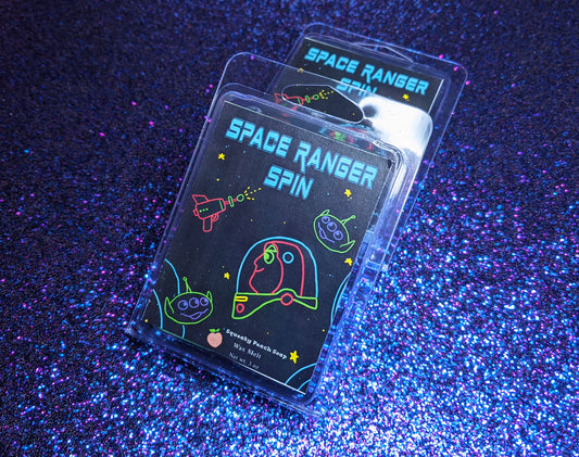 A deep blue wax melt label that pictures buzz lightyear and aliens. It reads "space ranger spin, squeaky peach soap, wax melt, 3 ounces"