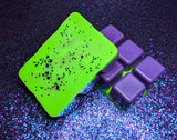 clamshell shaped wax with a purple base and neon green top. purple, silver, and green glitter on top.