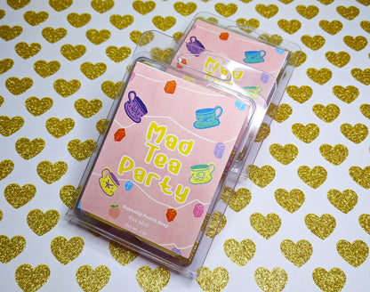 a pink wax melt label with tea cups and lanterns on it. It reads "Mad Tea Party, squeaky peach soap, wax melt, 3 ounces"